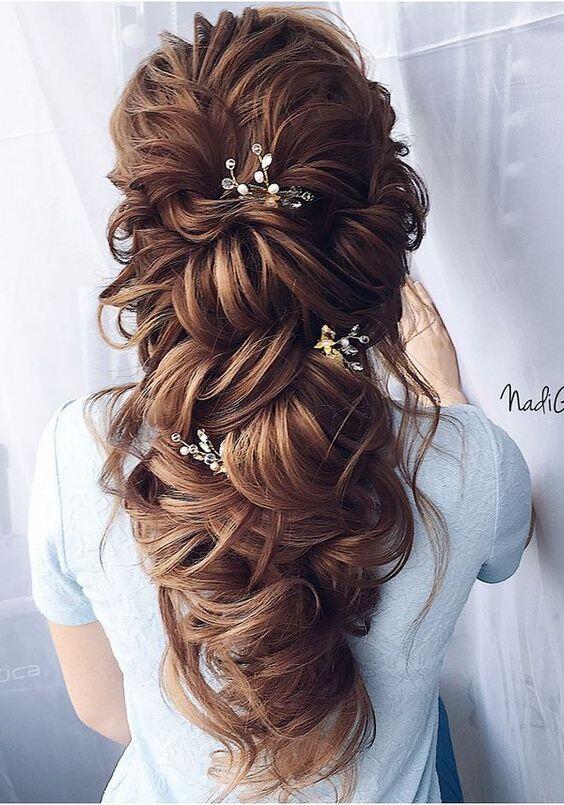 - This large boho princess bridal style has been the number 1 hair request for my 2019 brides. This style makes people think your hair is down, but is actually a sneaky way to keep it off your shoulders and face! It requires a lot of hair extensions to get that super full look, unless you have naturally thick hair. Poke a few simple hair accessories through these tousled curls and you’ve achieved the most feminine look!